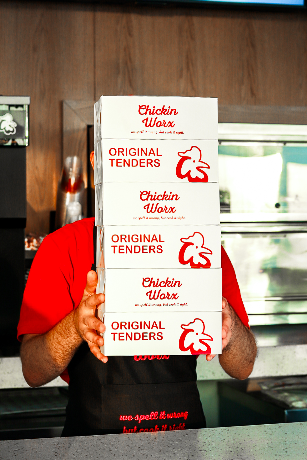 Chickin Worx team member holding a stack of Original Tenders boxes